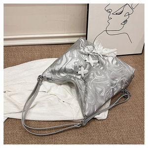 Close-up of silver wavy texture bag with white lace bow detail and metal chain strap