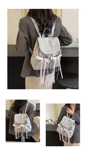 Detail of grey balletcore backpack featuring pink silk bow ribbons and NiKa embroidery