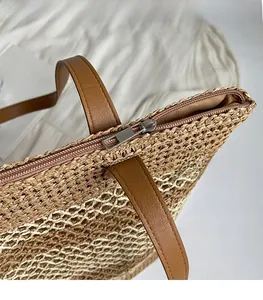 Detail shot of the smooth silver zipper closure and woven texture on a straw tote bag