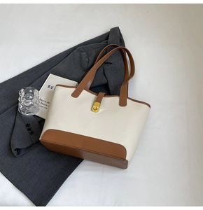 Detail of lychee pattern leather tote bag with contrast stitching and gold metal buckle