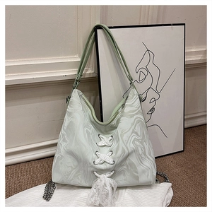 Detail of mint green marble tote bag featuring white lace-up ribbons and metal chain accents