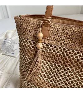Close-up of straw woven tote bag featuring leather tassels and decorative wood beads