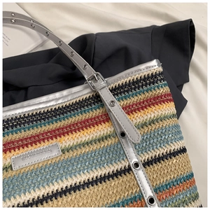Detail of multi-color striped straw tote bag with silver trim and metallic eyelets