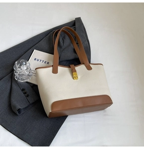 Detail of two-tone canvas tote bag with metal twist lock and pebble grain texture