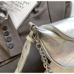 Détail du sac selle holographique argenté avec chaîne et texture froissée