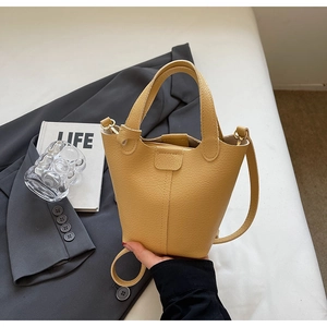Detail of yellow pebble leather bucket bag with vertical stitching and top handles