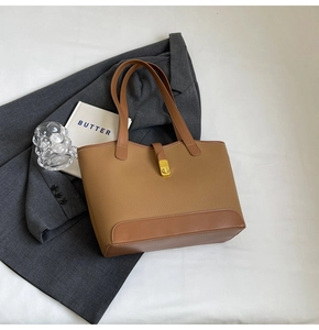 Detail of large tote bag with two-tone leather, pebbled texture and gold turn-lock closure