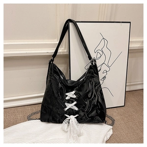 Detail of black marble textured leather tote with white lace-up bows and silver chain