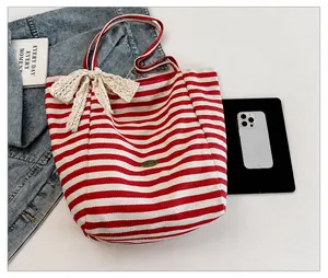 Detalle de bolso tote de lona a rayas rojas y blancas con lazo de encaje y emblema