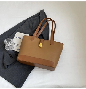 Macro detail of litchi texture brown leather tote bag with golden metal buckle