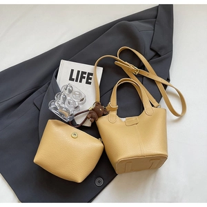 Close-up of yellow-brown leather bucket bag set with inner pouch and bear charm
