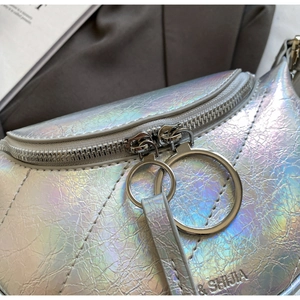 Détail du sac laser argenté avec surpiqûres en V et anneaux de fermeture éclair en métal