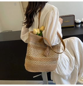Detail of hand-woven straw tote with hollow wave texture and brown leather strap