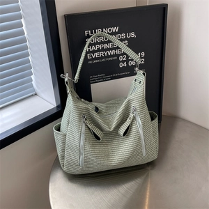 Large woven tote bag in light green with multiple zipper pockets and silver buckles