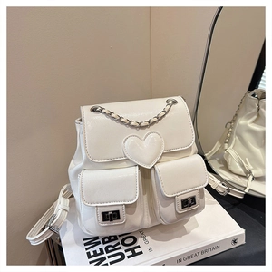 Detailed close-up of white mini backpack with heart charm and silver chain straps