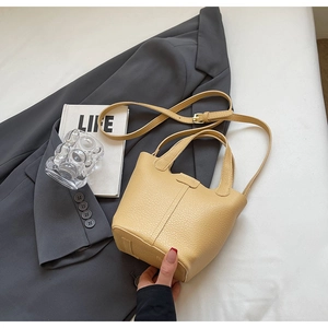 Detail shot of pale yellow pebbled leather bucket bag with top handle and strap