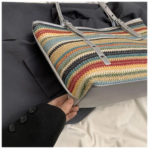 Detail of colorful striped straw tote bag featuring silver metallic straps and large capacity