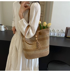 Detail of straw tote bag with woven hollow texture, leather straps and beaded tassels