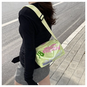 Detail of neon green jelly bag with graffiti prints and adjustable wide shoulder strap