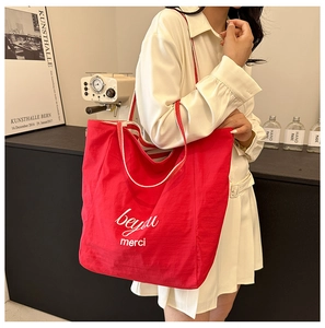 Detail of red canvas tote bag with beyou merci print and contrast shoulder straps