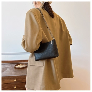 Detailansicht der schwarzen Schultertasche mit Litschi-Struktur und Kettenriemen am Model