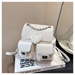 Detail of white faux leather backpack with heart design and silver chain decoration