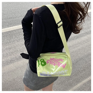 Outdoor shot of green graffiti jelly crossbody bag with pink lettering and wide strap