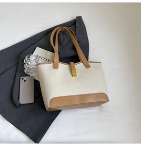Detailed top view of a cream leather tote bag with brown handles and a gold buckle lock