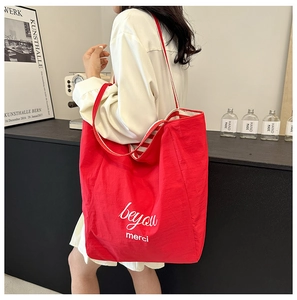 Detail of red canvas tote bag featuring white embroidery and striped lining detail