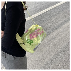 Detail of neon green transparent jelly bag with wide shoulder strap worn by a model
