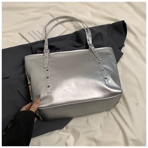 Detail of silver metallic tote bag with adjustable eyelet straps and embroidered accents