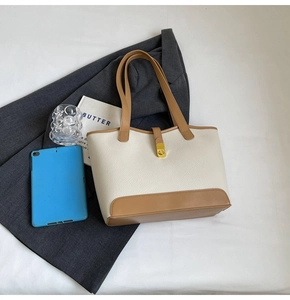 Detail of contrast tote bag with lychee texture leather and golden metal lock