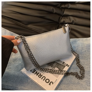 Details der silbernen Lederstruktur und Metallkette an einer modernen kleinen Tasche