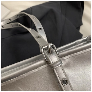 Detail shot of the silver metallic tote bag with eyelet straps and adjustable buckle