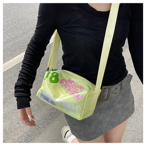 Detail of light green glossy jelly bag featuring pink graffiti art and wide shoulder strap