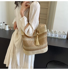 Detail of multi-color woven straw tote bag with brown leather strap and long tassel