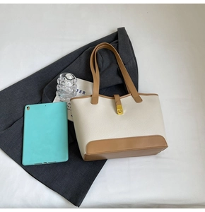 Top-down view of a spacious beige tote bag with brown straps and gold metal buckles