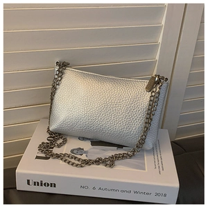 Detail der silbernen Tasche mit Litschi-Struktur und schwarzer Metallkette auf Magazin