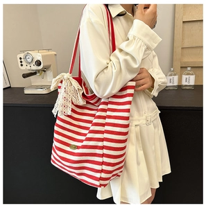 Close-up of red striped canvas tote bag featuring lace bow and handmade label detail