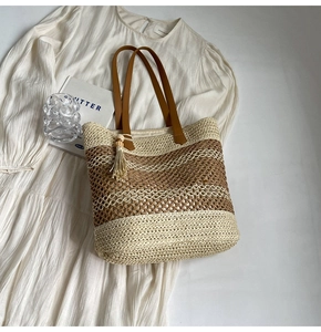 Detailed top view of striped straw tote bag with brown leather handles and fringe tassel