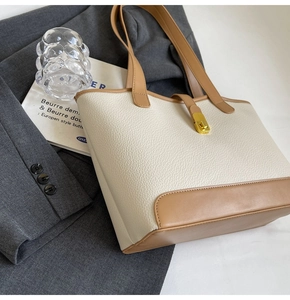 Detail of a cream and brown leather tote bag featuring a gold twist-lock closure
