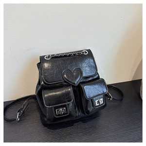 Detail of black faux leather backpack with heart motif and silver chain accent