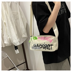 Detail of off-white crossbody bag featuring bold 18 and fashion graffiti with wide strap