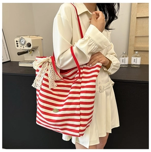 Detail of red striped canvas tote bag with cream lace bow and handmade metal plaque