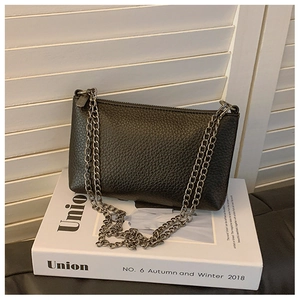 Detailaufnahme der schwarzen Umhängetasche aus Lychee-Leder mit dunkelgrauer Metallkette