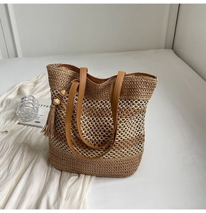 Detail of straw woven tote bag featuring hollow mesh texture and brown leather straps