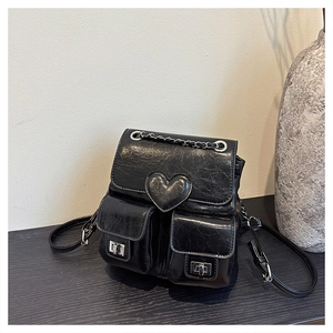 Detail of black crackle leather mini backpack featuring heart motif and silver twist locks