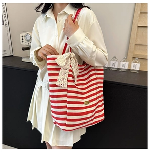 Detail of red and white striped tote bag with a large cream lace bow decoration