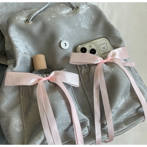 Dettaglio dello zaino grigio metallizzato con grandi fiocchi di raso rosa e tessuto testurizzato