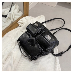 Detail of black faux leather backpack with silver turn-lock pockets and heart patch